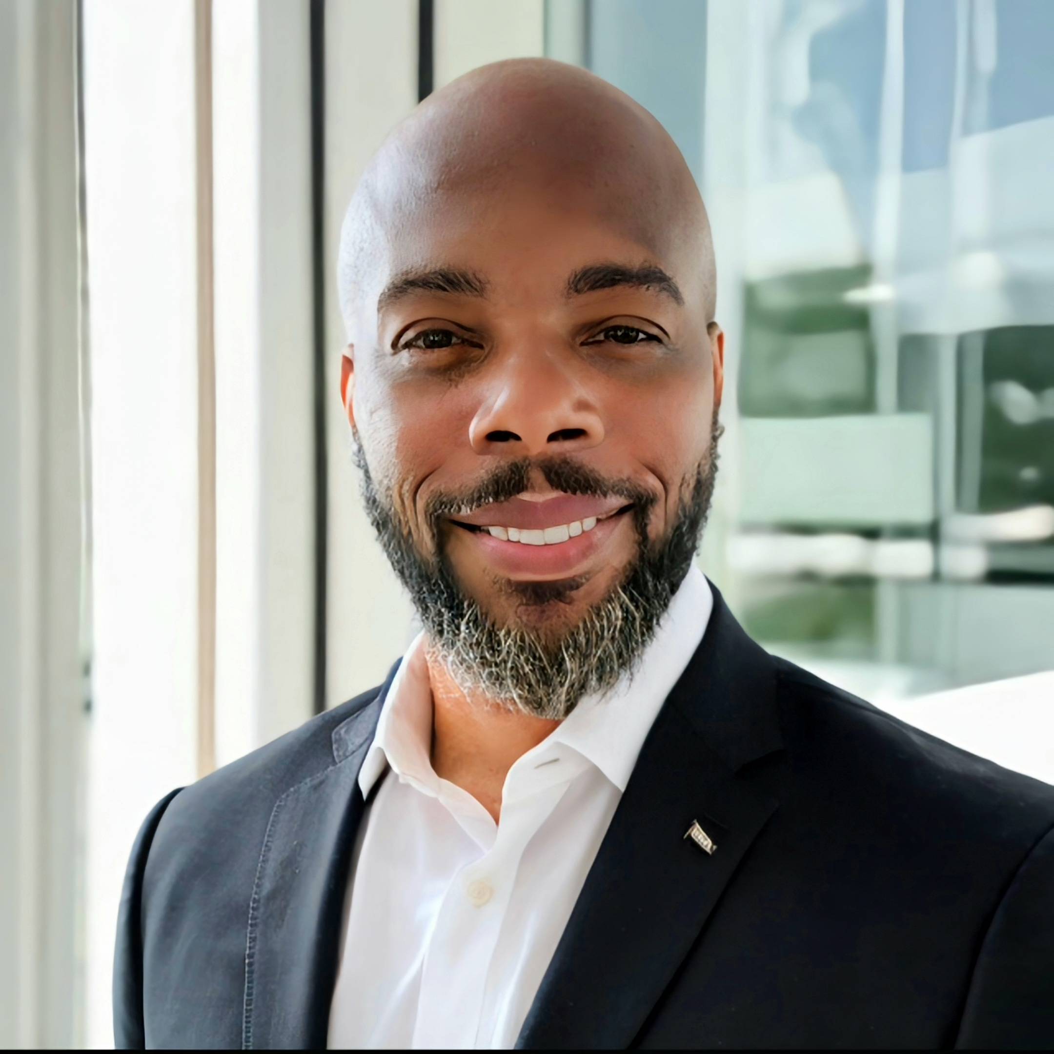 Larnel Hight for RenderDefense in a suit smiling in front of a window